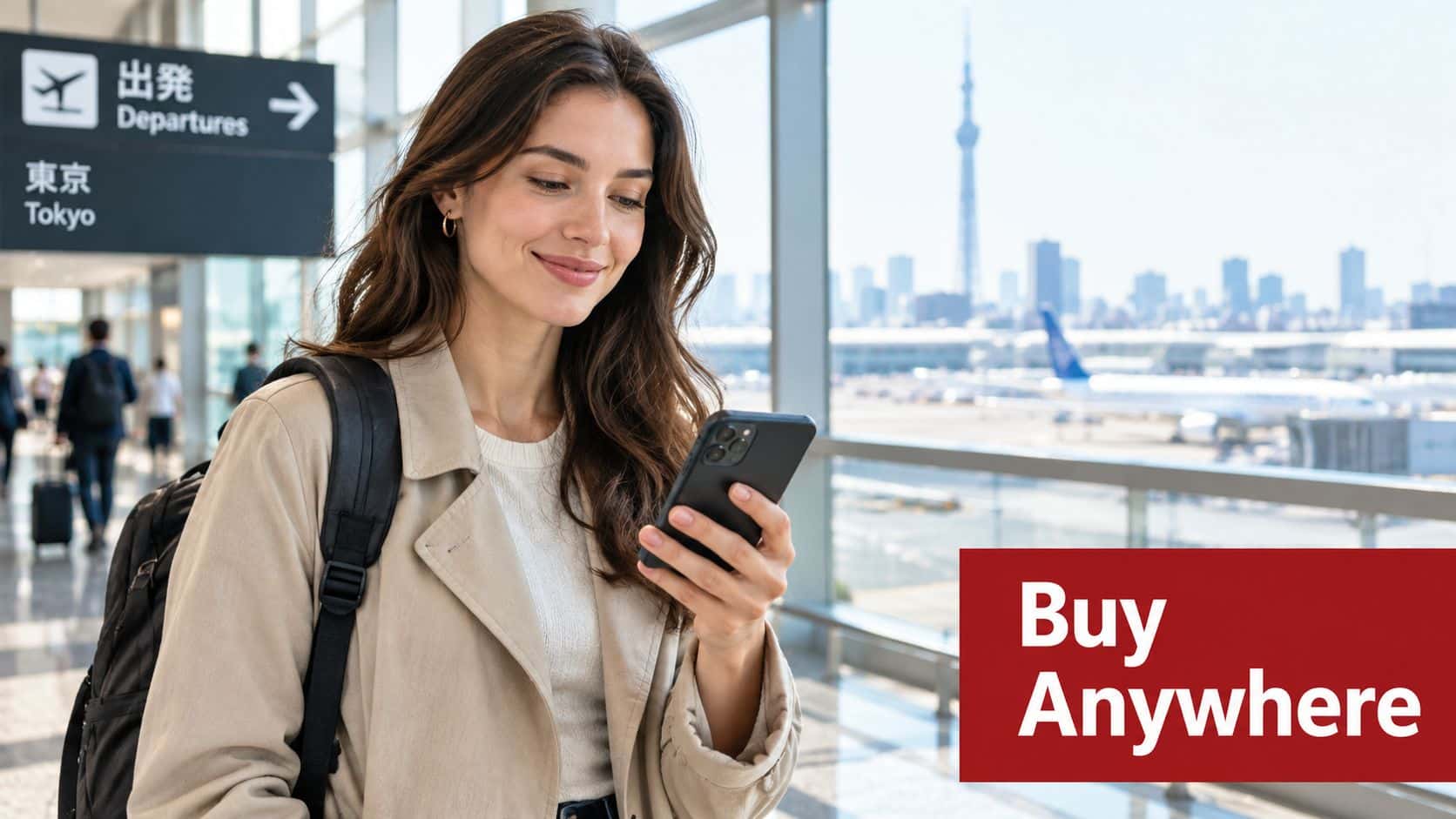 A smiling woman holding a smartphone at an airport terminal in Japan with the Tokyo Skytree visible.